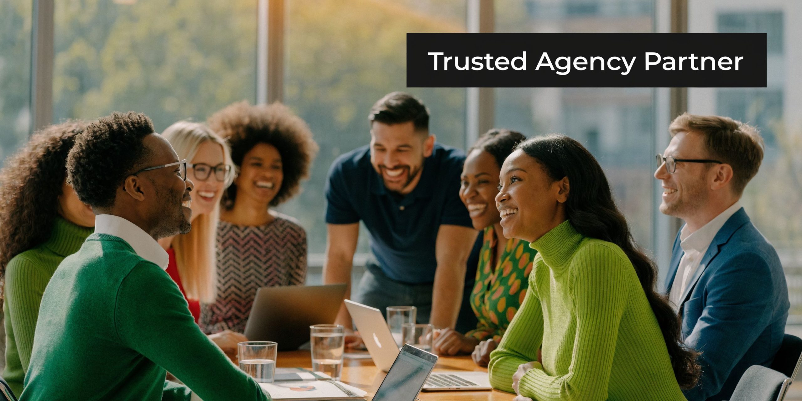 A diverse group of professional colleagues smiling and collaborating during a business meeting in a modern office.